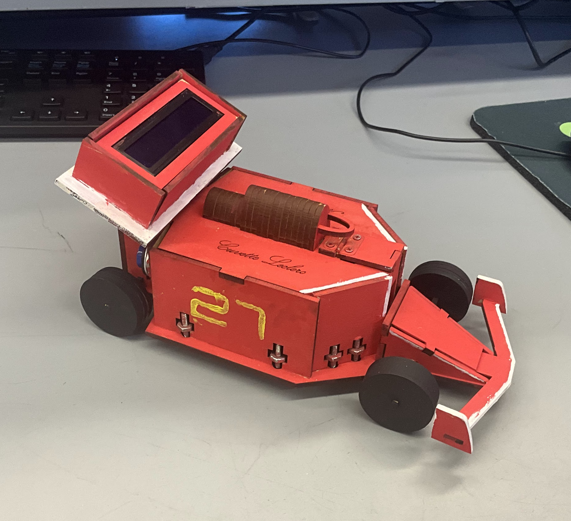 Assembled Arduino spectrophotometer styled as a red Ferrari Formula 1 car, with black wheels, a front wing, a sample opening, and a raised LCD housing